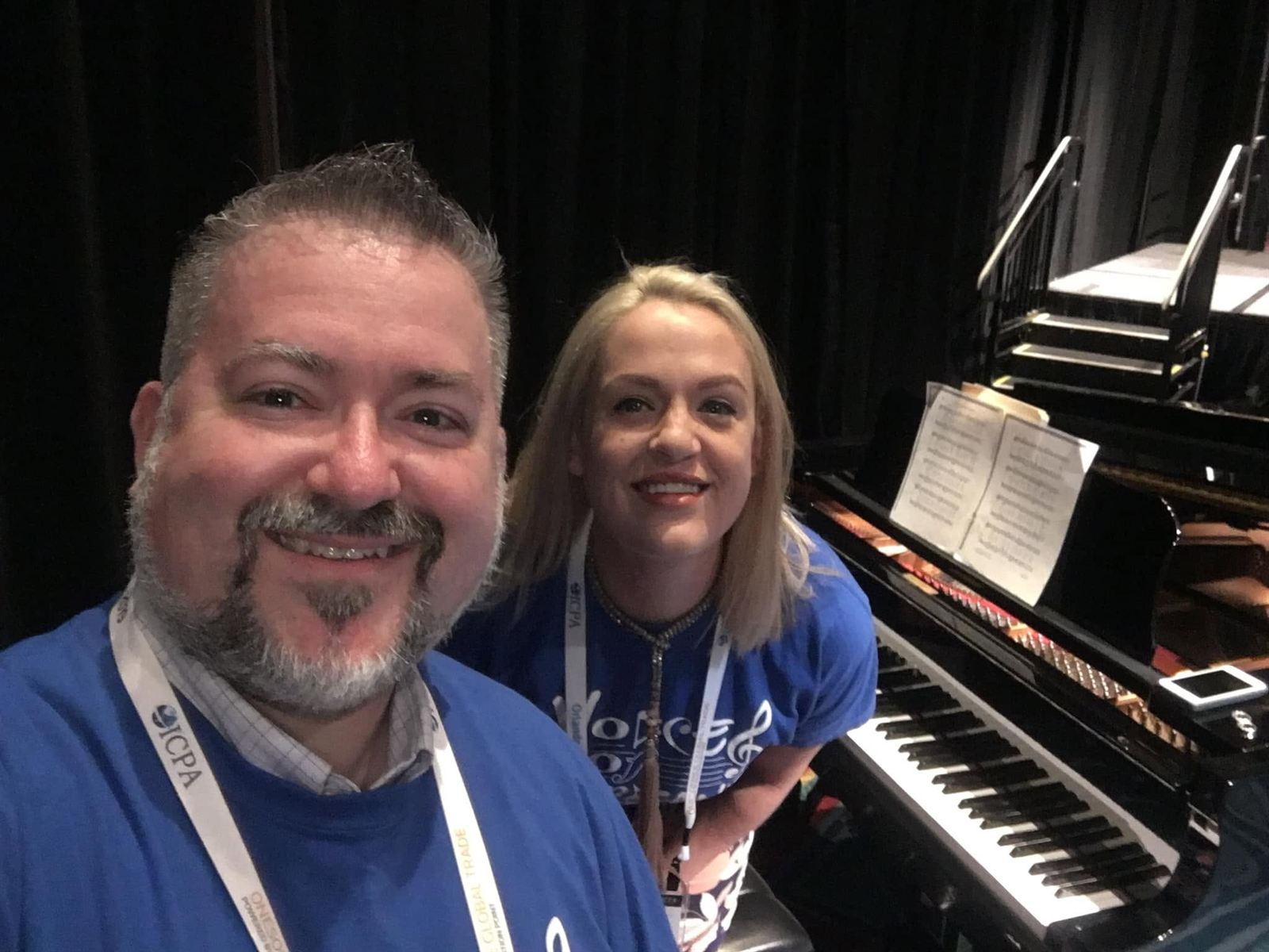 Two choir members in Voices of Compliance shirts at the piano before a performance.