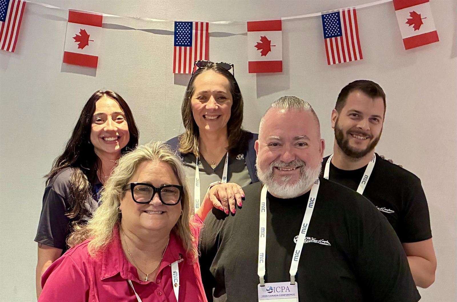 Five choir members smiling under a string of US and Canadian flags.