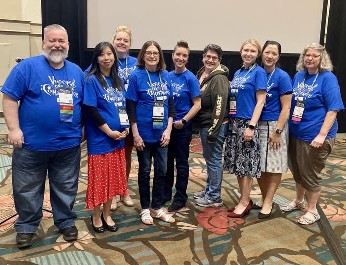 Ten choir members standing together in blue Voices of Compliance shirts in Orlando.